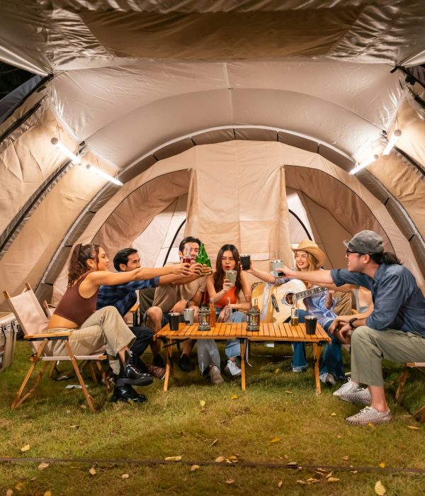 Group of diverse friend having outdoors camping party together in tent.